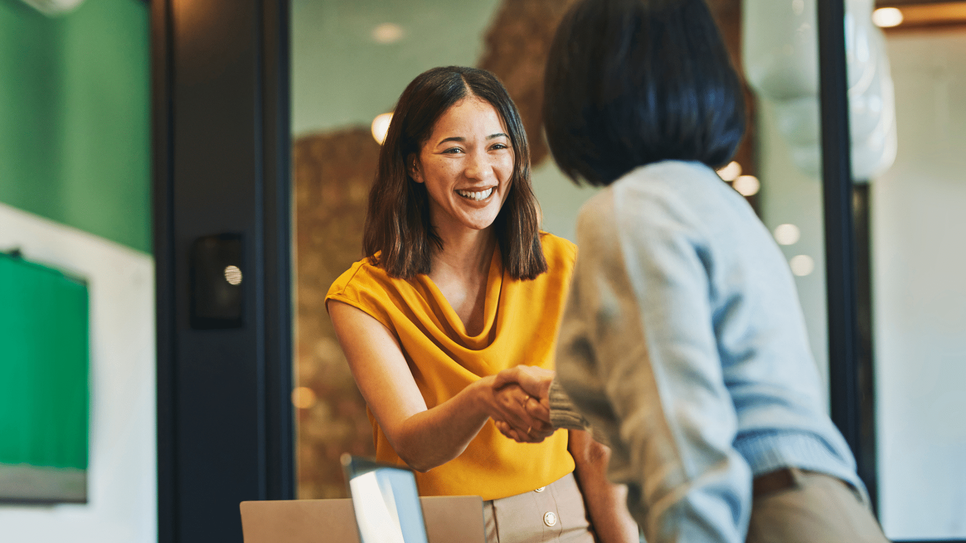 A business executive shakes hands with her leadership coach.